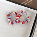 Primer plano de pendientes de corazón de peluche coloridos con textura tejida en bandeja - Corazón Rojo Azul
