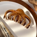 Detail of a large amber resin hair claw clip with wood texture on a minimal white tray - Multi-Tooth Claw Clip