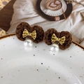 Close-up of caramel knitted earrings with gold bow and elegant pearl drop detail - Coffee