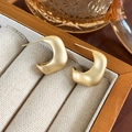Detalle de pendientes geométricos en forma de C oro mate en una bandeja de joyas beige - Dorado Mate (24486A)
