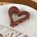 Close-up of velvet-flocked heart hair claw clip in caramel brown on a ceramic plate - Khaki Heart
