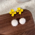 Detail von gelben Blumenohrringen mit weißem Bommel auf strukturiertem Hintergrund - Stil B Lange Hängeohrringe(24497B)