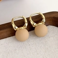 Dettaglio di orecchini a cerchio geometrici con perline beige opache su vassoio in legno - Orecchini a Cerchio con Sfera Opaca (22177A)
