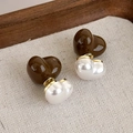 Primo piano di orecchini vintage a cuore in marrone e bianco perla su tessuto beige - Orecchini a Bottone a Cuore Bicolore (24129C)