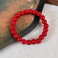 Dettaglio macro del bracciale di perle di agata lucida bordeaux su sfondo di tela vintage - Stile a Perline Rosse Singole