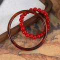 Dettaglio di braccialetti con perline rosse e cerchi in tartaruga in un vassoio di legno - Bracciale Perline Rosse E Bracciale Rigido Tartarugato