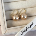 Foto macro de pendientes de perlas champán en estuche de joyería con cinta decorativa - Perla Artificial Champaña (12mm)