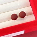 Primo piano di orecchini a perno con perle rosso opaco in un portagioie in velluto beige - 12mm / Rosso Scuro