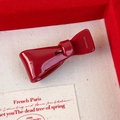 Vista macro di un fermaglio a fiocco rosso lucido con incisione Handmade su velluto - Fiocco Asimmetrico
