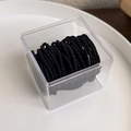 Close-up of black elastic hair ties with ribbed texture in a clear plastic storage box - Pure Black (18104D)