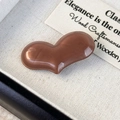 Detail of a glossy heart-shaped acetate hair clip with a vintage pearlescent brown finish - Coffee