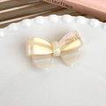 Detail view of a pearlescent acetate bow hair clip with gold France Handmade logo - Cream White Bow Style (24826B)