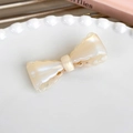 Detailed macro of cream acetate bow hair clip with pearlescent finish on a white plate - Cream White Lace Edge Style (24826C)