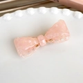 Close-up of a pink acetate bow hair clip with marble texture on a white lace plate - Pink Lace Edge Style (24826G)