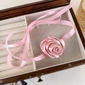 Macro view of a 3D pink satin rose flower choker with long adjustable silk ribbons - Pink