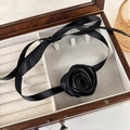 Detail of a black satin ribbon choker with a handmade 3D fabric rose on a wooden box - Black