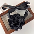 Macro shot of large black fabric flower choker with satin ribbons in a wooden box - Black Flower (24861B)
