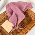 Dettaglio di un foulard a quadretti rossi con lacci in un cesto di vimini - Quadri Rosso Bianco
