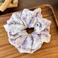 Detalle de coletero floral lavanda con textura de malla sobre bandeja de madera - Morado