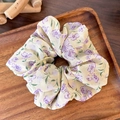 Detalle de un coletero de gasa floral con flores violetas en una bandeja de madera - Amarillo