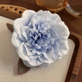 Vista macro della clip per capelli a forma di peonia blu sfumata con petali strutturati - Celeste