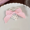 Detail of pink ribbon bow hair clip with white heart crochet lace on ceramic plate - Pink