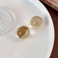 Detail of translucent amber resin ball earrings with polished finish on a white plate - Transparent Yellow