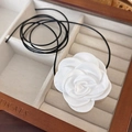 Close-up of a white fabric camellia flower choker necklace on a soft beige velvet lining - 21# White Satin Camellia (24443A)