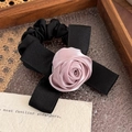 Gros plan sur un chouchou noir élégant avec une rose en satin et un nœud soyeux - Rose Violet