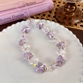 Macro detail of purple butterfly charm strap with aurora effect beads on a white plate - Purple Iridescent