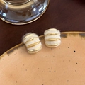 Dettaglio ravvicinato di orecchini a onde dorate con lana bianca su piatto ceramico - Stile Avvolto in Lana (21# 24439A)