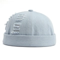 Dettaglio del cappello docker in denim azzurro con fori usurati e bordo arrotolato retrò - Azzurro