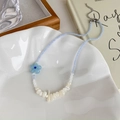 Detalle de collar de cuentas azules con flor y perlas blancas sobre un plato de cerámica - Estilo de Concha de Cuentas de Flores Azules (Estilo de la Imagen Principal)