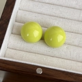 Dettaglio di orecchini a lobo in resina verde lime su un espositore in velluto beige - Verde