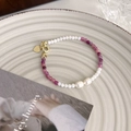 Detail von Süßwasserperlen-Armband mit lila Perlen und Goldherz-Anhänger auf Keramikausteller - Lila und Weiße Perle