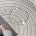 Dettaglio del bracciale con perline d'argento irregolari e ciondolo quadrato su piatto - Quadrato Argento