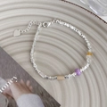 Dettaglio del bracciale con perline d'argento, ciondoli colorati e cuore su vassoio - Bambù di giada