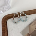 Detail of beaded hoop earrings with blue and brown stones on white linen fabric - Blue