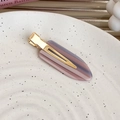 Dettaglio del fermaglio a becco d'anatra in acetato rosa Morandi su un piatto di ceramica - Stile Goccia d'acqua Scura