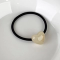 Macro shot of cream heart resin hair tie with La France gold script on a white dish - Beige Heart
