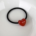 Detailed macro view of a red acrylic heart hair tie featuring elegant gold lettering - Red Heart