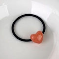 Detail of pink heart-shaped acrylic hair tie with gold lettering on white ceramic tray - Light Orange Heart