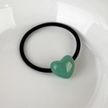 Close-up of a mint green heart charm on a black elastic hair tie on a white ceramic plate - Green Heart