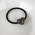 Close-up of minimalist heart hair tie with golden lettering on a white porcelain plate - Grey Heart