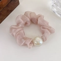 Dettaglio di uno scrunchie in organza rosa chiaro con una grande perla iridescente su bianco - Rosa