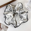Primer plano de un coletero grande de satén crema con elegantes flores negras - A Flor Negra sobre Blanco