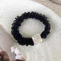 Detail of black organza scrunchie with a square mother-of-pearl bead on a tray - Black