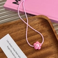 Rosa Perlen Handykette mit Blumenanhänger auf dekorativem Holztablett im Detail - Rosa Blume