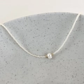 Detailed close-up of a minimalist necklace featuring a baroque pearl and white seed beads - White Beads