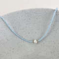 Detail of blue beaded necklace featuring a white freshwater pearl and golden accents - Sky Blue Beads